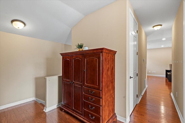 corridor with hardwood / wood-style floors and vaulted ceiling