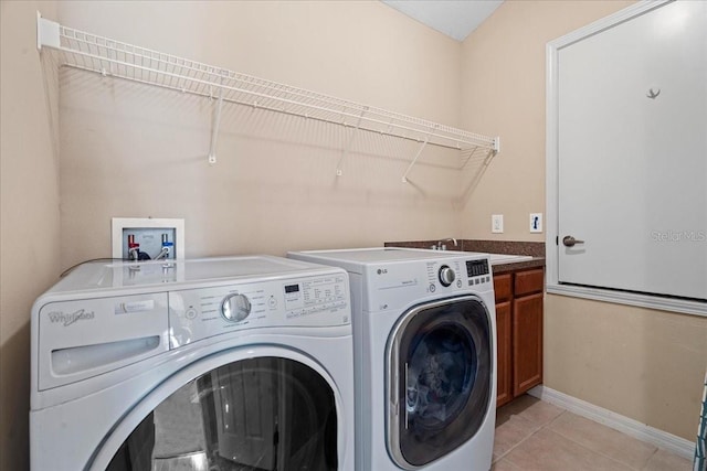 washroom with light tile patterned floors, cabinets, and washer and clothes dryer