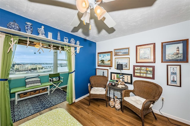 living area with hardwood / wood-style floors, a textured ceiling, and ceiling fan