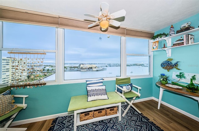 sunroom featuring ceiling fan and a water view