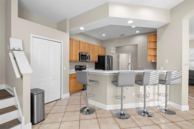 kitchen featuring a kitchen bar, kitchen peninsula, light tile patterned floors, and appliances with stainless steel finishes