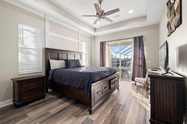 bedroom with access to exterior, dark hardwood / wood-style floors, a raised ceiling, and ceiling fan