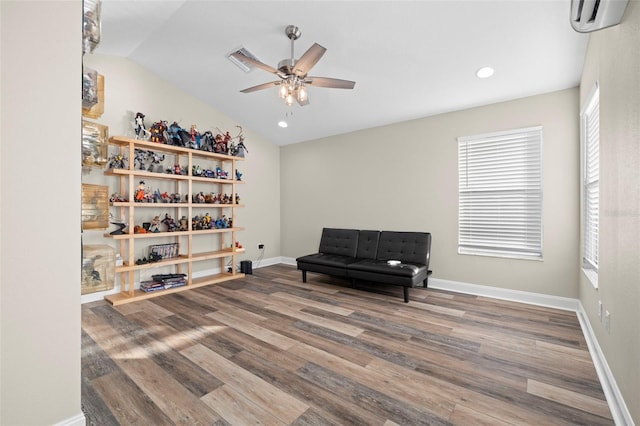 sitting room with wood-type flooring, an AC wall unit, ceiling fan, and lofted ceiling