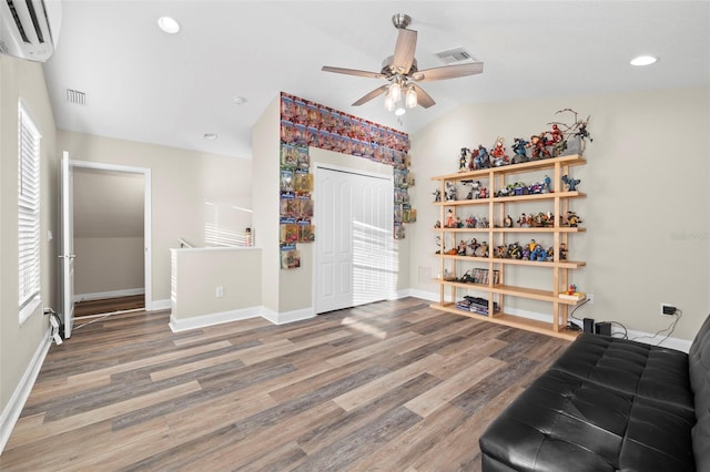 interior space with a wall unit AC, ceiling fan, wood-type flooring, and vaulted ceiling