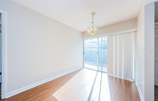 empty room featuring a chandelier and wood-type flooring