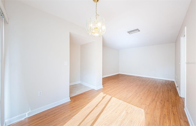 unfurnished room featuring hardwood / wood-style floors and an inviting chandelier