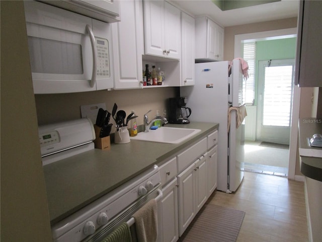 kitchen featuring white cabinets, white appliances, plenty of natural light, and sink