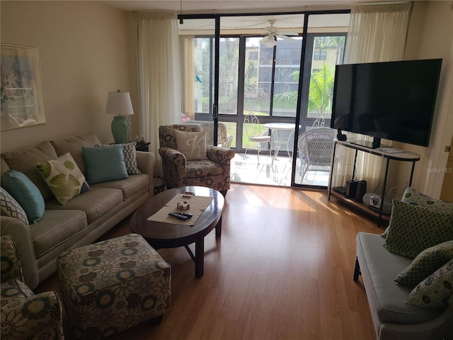 living room featuring light wood-type flooring, a wall of windows, and ceiling fan