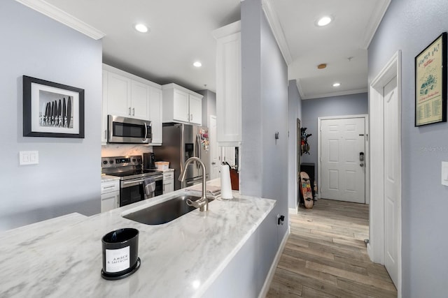 kitchen featuring appliances with stainless steel finishes, ornamental molding, light stone counters, white cabinets, and sink