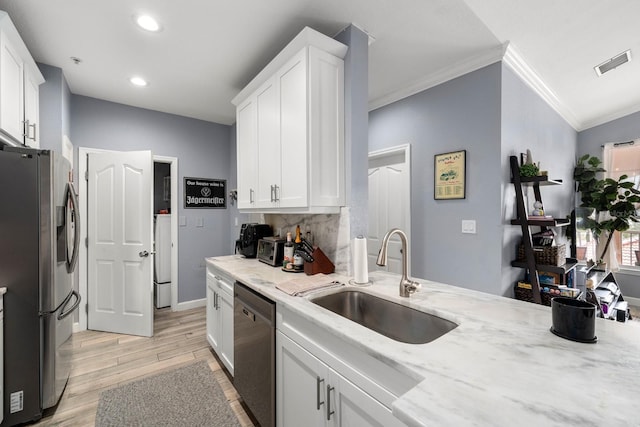 kitchen featuring light stone counters, stainless steel appliances, crown molding, white cabinets, and sink