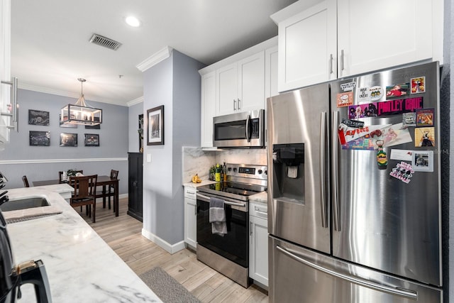 kitchen with stainless steel appliances, white cabinets, light hardwood / wood-style flooring, light stone countertops, and crown molding