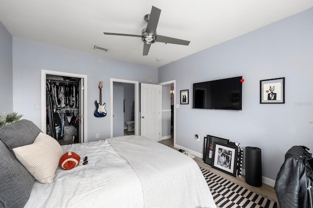 bedroom with connected bathroom, a closet, hardwood / wood-style floors, ceiling fan, and a walk in closet