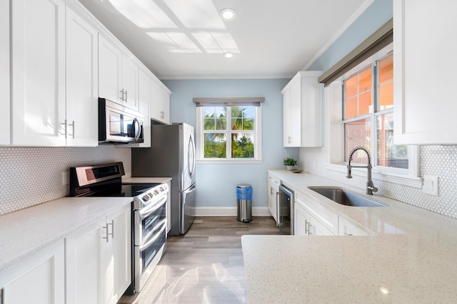 kitchen featuring sink, white cabinetry, light hardwood / wood-style floors, light stone countertops, and appliances with stainless steel finishes