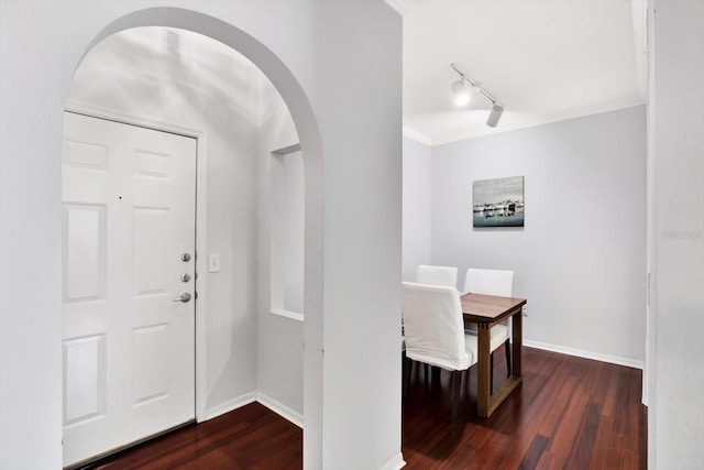 foyer entrance with crown molding, dark wood-type flooring, and track lighting