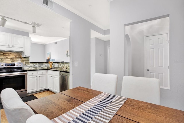 kitchen with decorative backsplash, white cabinetry, sink, and stainless steel appliances