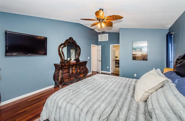 bedroom with vaulted ceiling, ensuite bathroom, dark hardwood / wood-style flooring, ceiling fan, and a textured ceiling