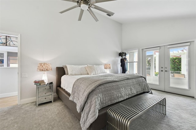 bedroom with a high ceiling, access to outside, french doors, ceiling fan, and light colored carpet