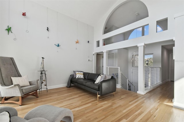 living room with a towering ceiling, hardwood / wood-style flooring, and decorative columns