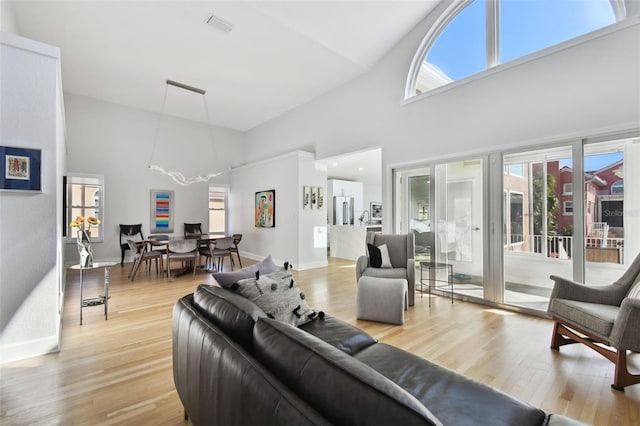 living room with light wood-type flooring and high vaulted ceiling