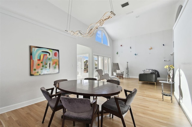 dining area with hardwood / wood-style floors and high vaulted ceiling