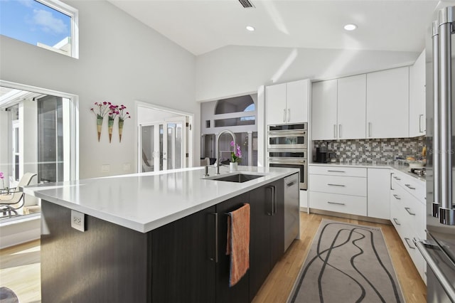 kitchen with a kitchen island with sink, sink, white cabinets, and stainless steel appliances