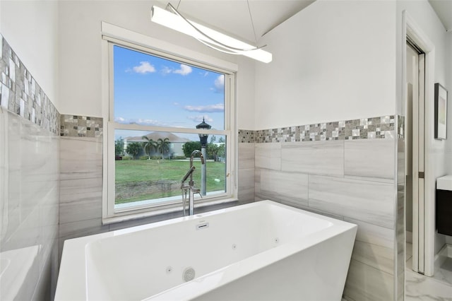 bathroom featuring a wealth of natural light, a bathtub, tile walls, and sink