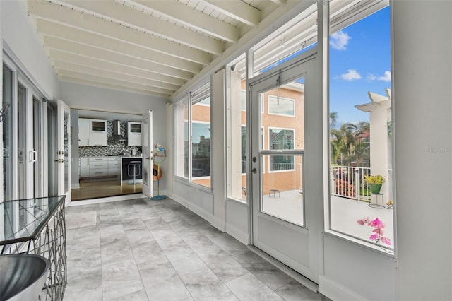 unfurnished sunroom with beam ceiling and plenty of natural light