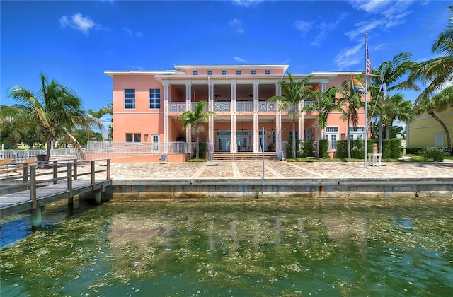 back of property with a balcony and a water view