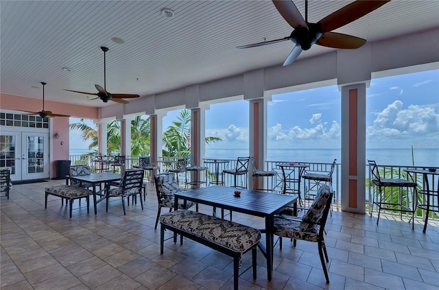 sunroom / solarium featuring ceiling fan, a water view, and french doors