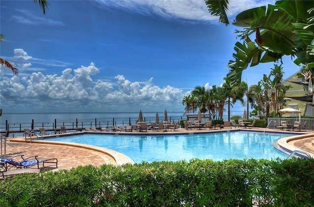 view of swimming pool featuring a water view and a patio