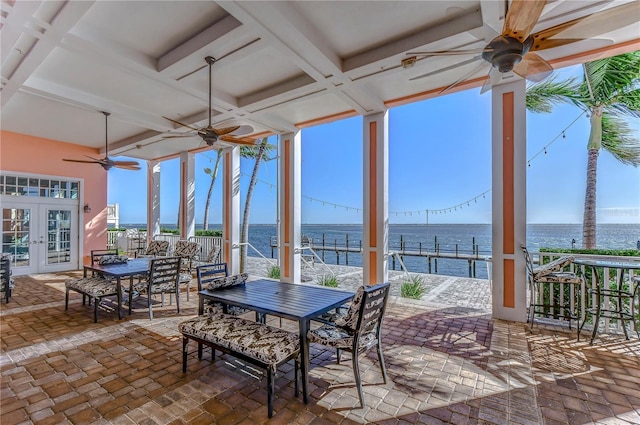 sunroom / solarium featuring french doors, a water view, a wealth of natural light, and ceiling fan