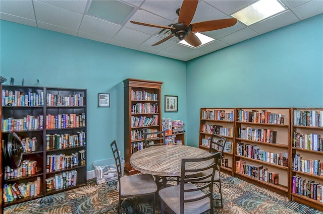 interior space with a paneled ceiling and ceiling fan