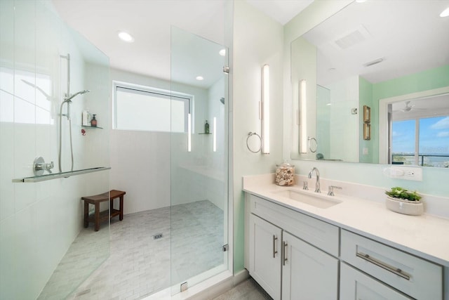 bathroom with a tile shower, a wealth of natural light, and vanity