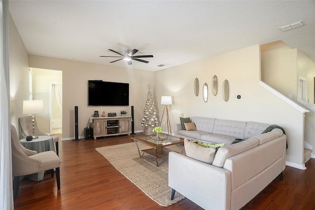 living room with ceiling fan, dark wood-type flooring, and a textured ceiling