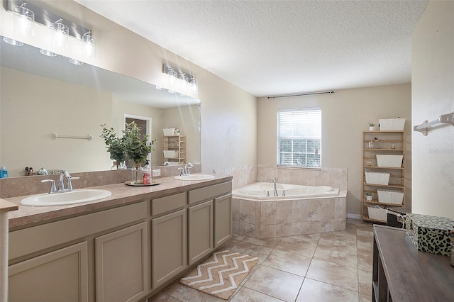 bathroom featuring vanity, a textured ceiling, a relaxing tiled tub, and tile patterned flooring