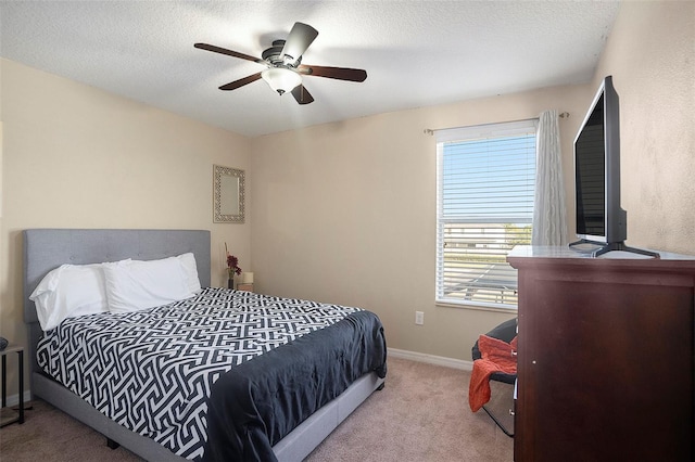 bedroom with a textured ceiling, ceiling fan, and light carpet