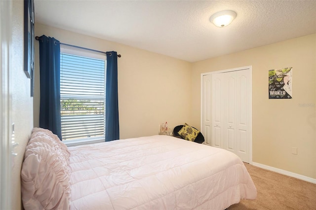 bedroom featuring a textured ceiling, light colored carpet, and a closet