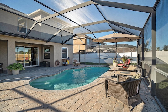 view of swimming pool with glass enclosure, ceiling fan, and a patio area