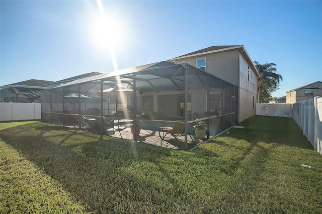 rear view of property featuring a lanai, a lawn, and a patio