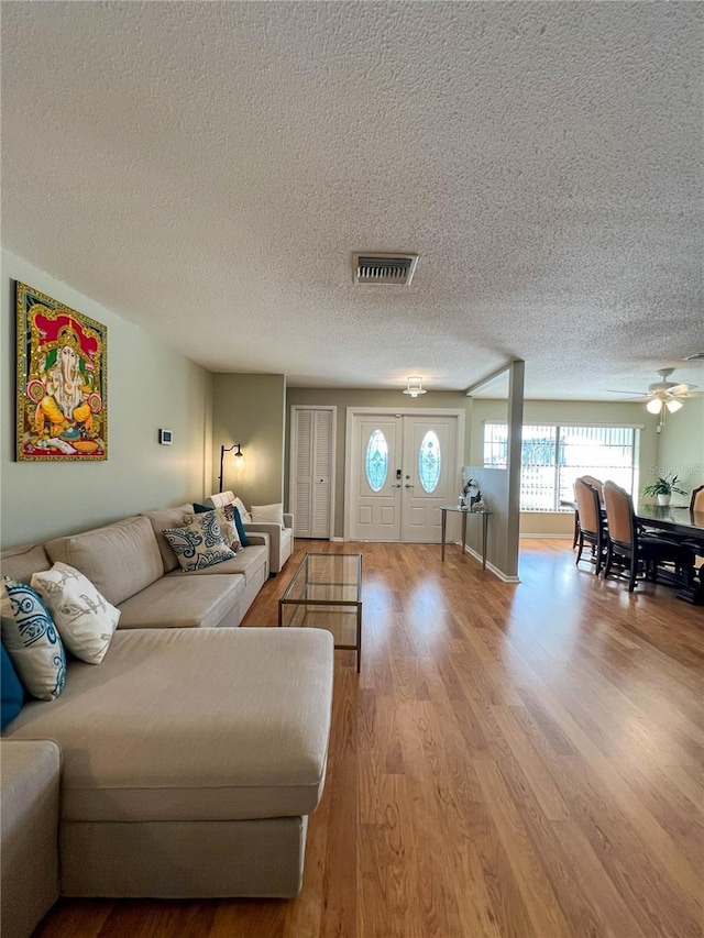 living room featuring a textured ceiling, ceiling fan, and light hardwood / wood-style floors