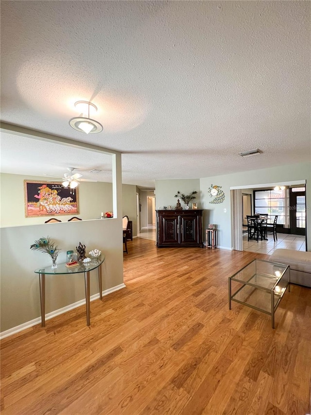 living room with ceiling fan, wood-type flooring, and a textured ceiling