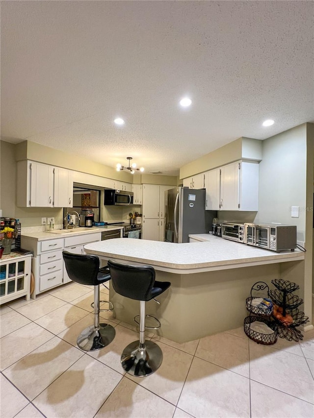 kitchen with a breakfast bar, white cabinets, stainless steel appliances, and light tile patterned flooring