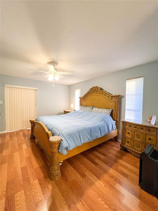 bedroom featuring ceiling fan, light hardwood / wood-style floors, and a textured ceiling