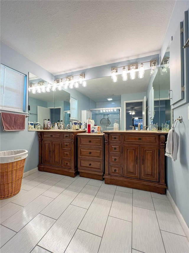 bathroom featuring a shower with shower door, a textured ceiling, and vanity