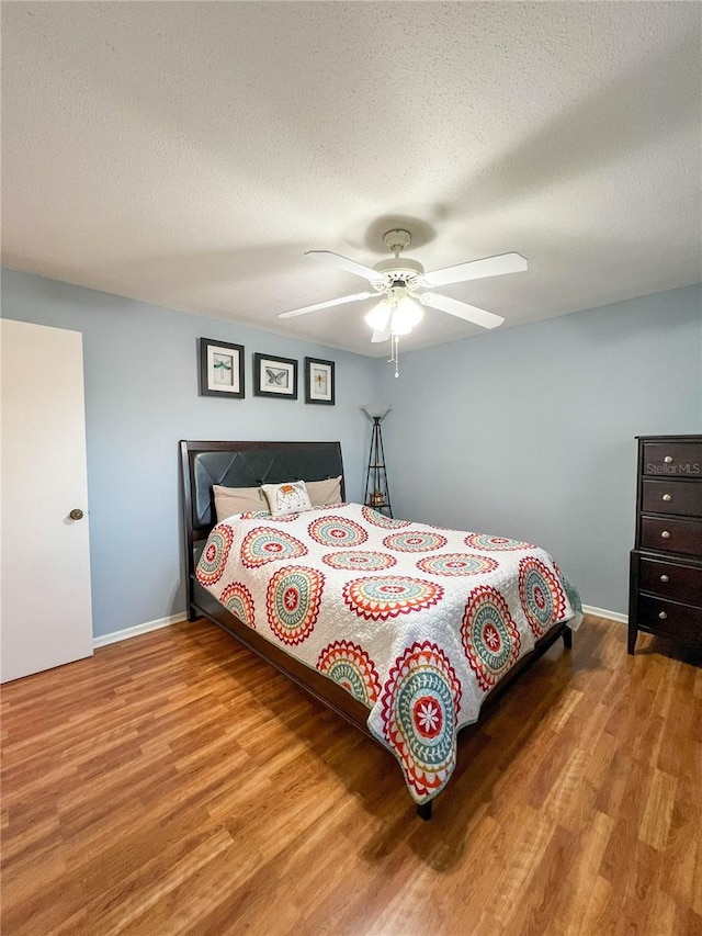 bedroom with ceiling fan, a textured ceiling, and hardwood / wood-style flooring