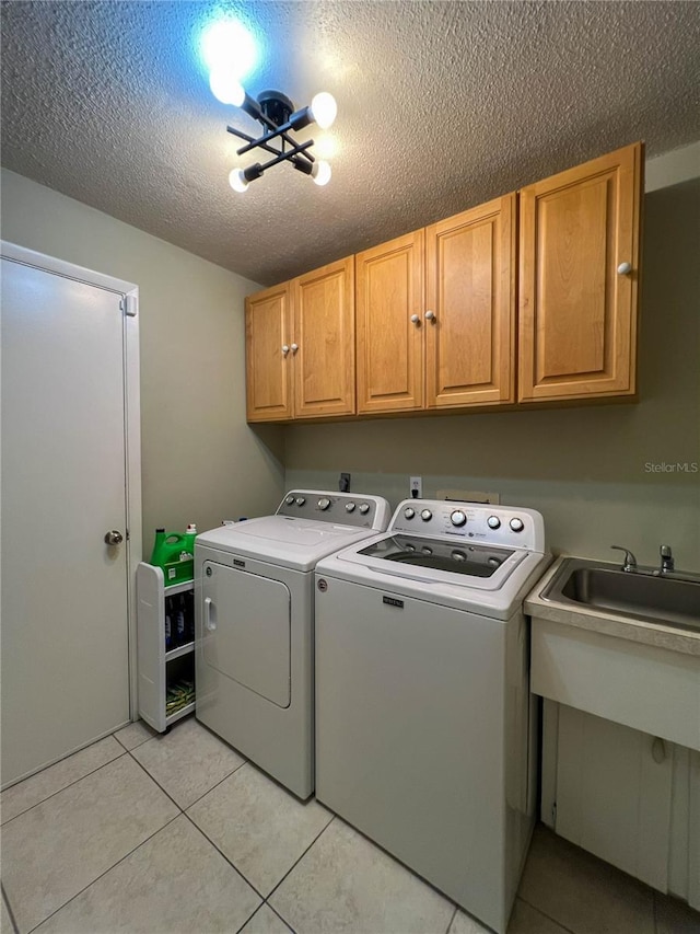 laundry area featuring cabinets, a textured ceiling, independent washer and dryer, and light tile patterned flooring