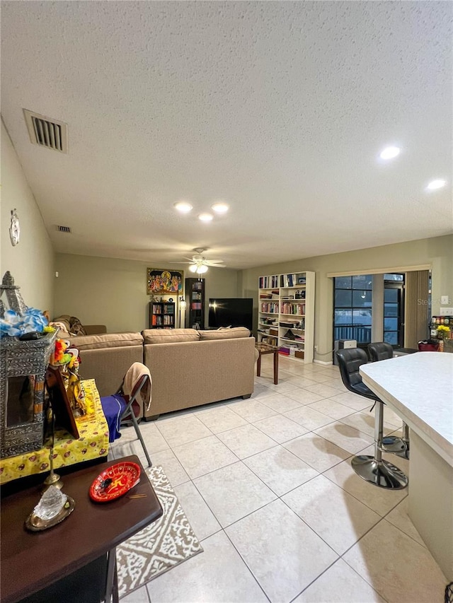 living room featuring ceiling fan, light tile patterned floors, and a textured ceiling