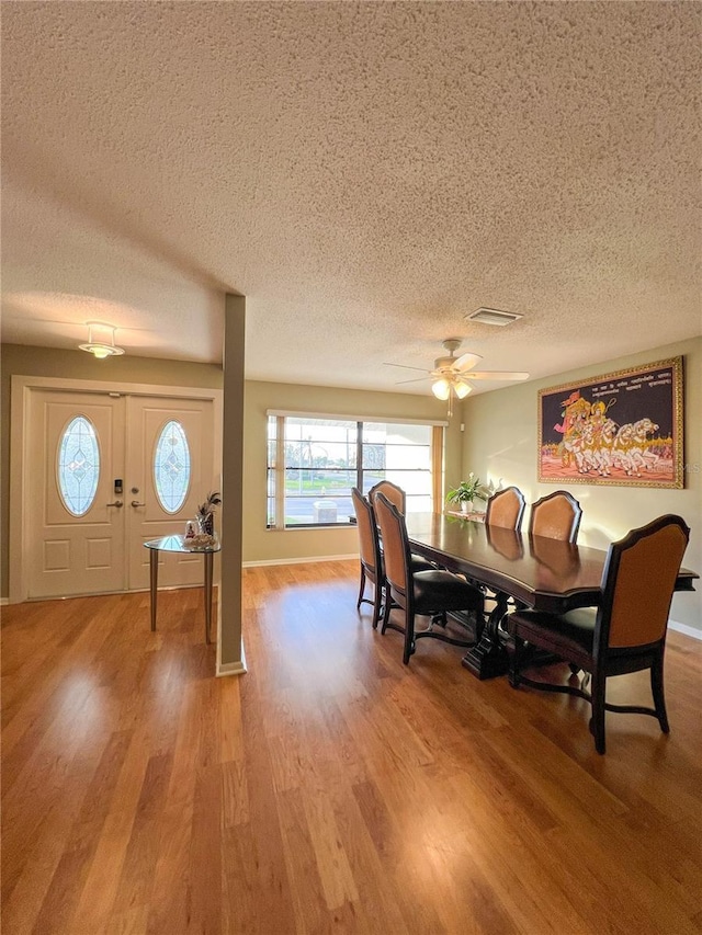 dining area with a textured ceiling, ceiling fan, and hardwood / wood-style flooring