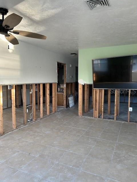 unfurnished living room featuring visible vents and a ceiling fan