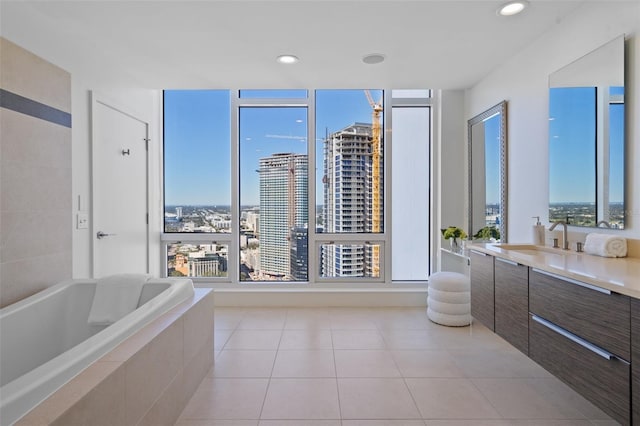 bathroom with tile patterned floors, vanity, and a relaxing tiled tub